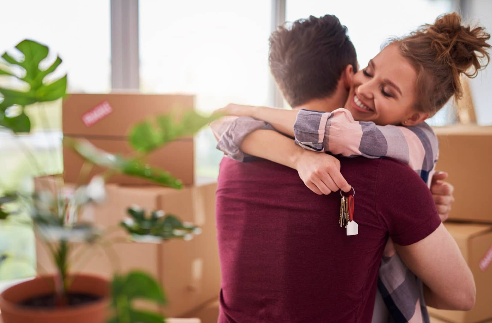 Happy couple hugging with keys of new house